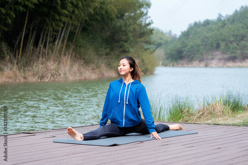 Fototapeta premium A young Asian woman practicing yoga in the outdoors