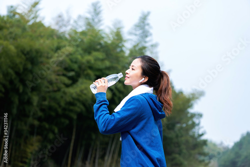 A young Asian woman drinking water during outdoor exercise