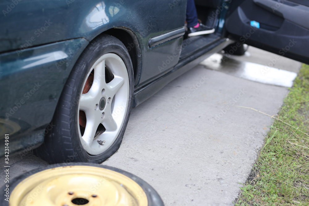 Flat tyre on road. Car tire leak because of nail pounding. Wheel damage on a road. Flat tyre on road. Car tire leak because of nail pounding. Wheel damage on a road.