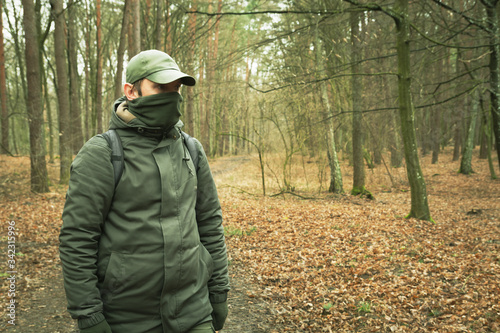 A man with a covered face looking around in an autumn forest © darekb22