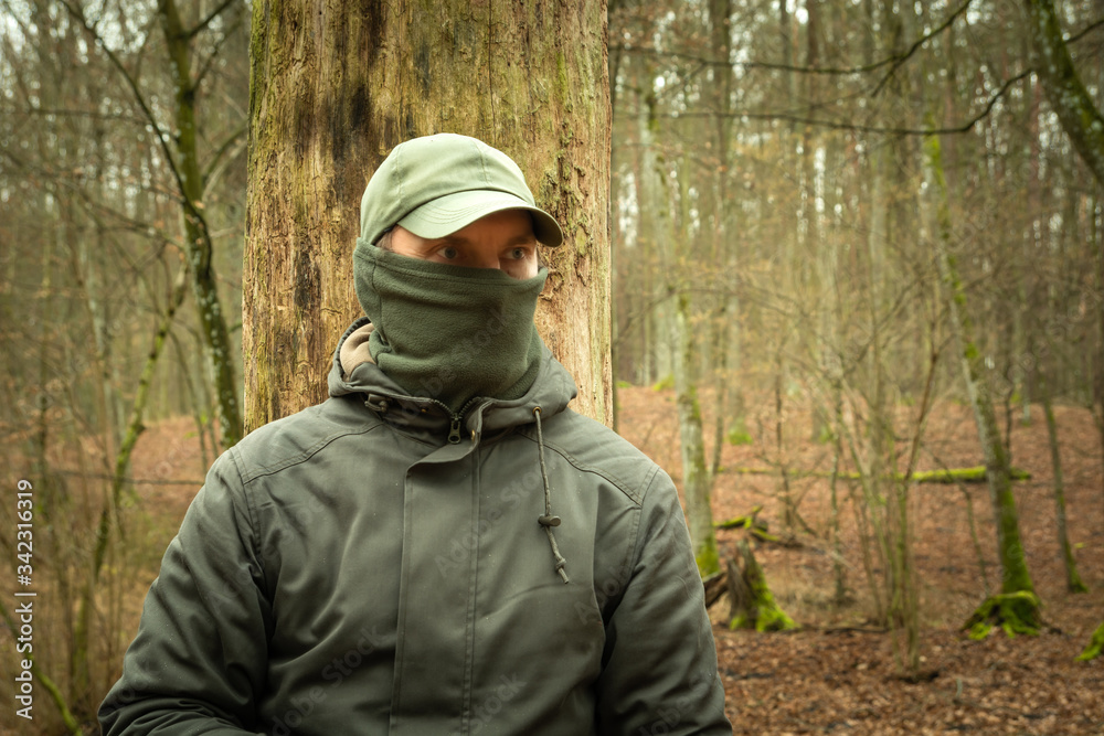 Man with covered face looking into the forest