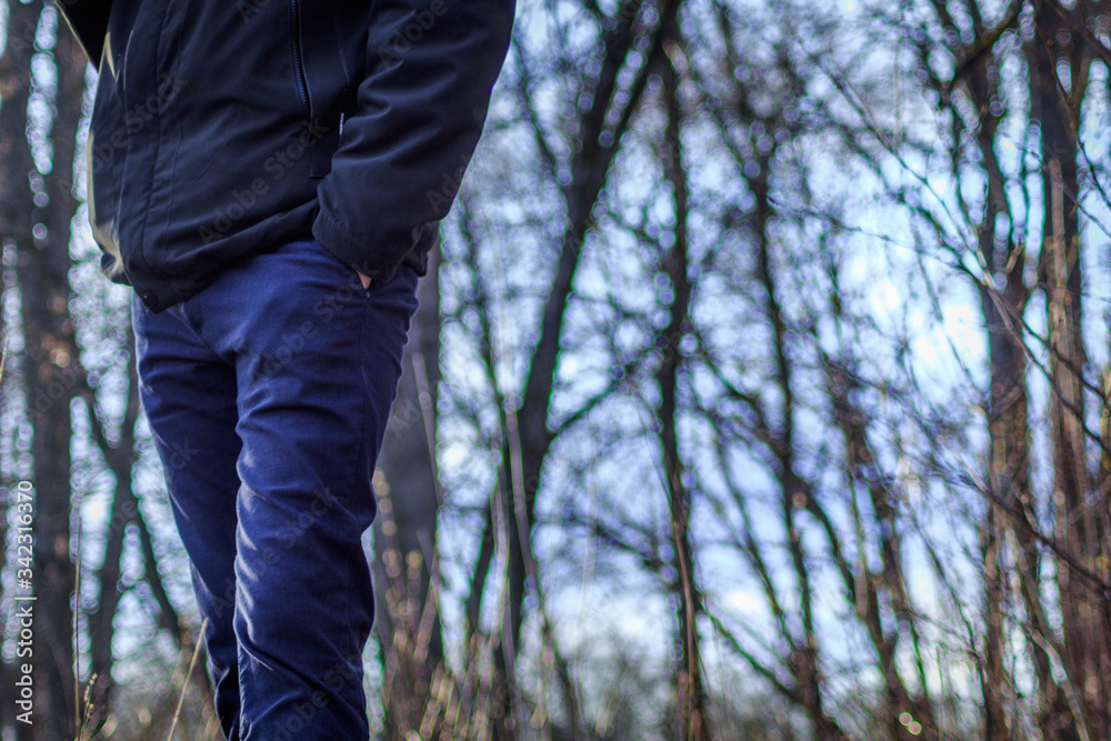 A tall young man in a jacket and jeans stands on the street, his hands are hidden in his pockets. A tall young man in a jacket and jeans stands on the street, his hands are hidden in his pockets.