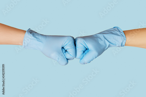 Hands in medical gloves greeting each other with fist bump.