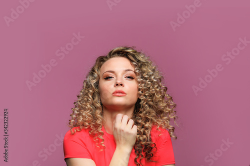 beautiful young woman with curl hair posing on pink background - Image