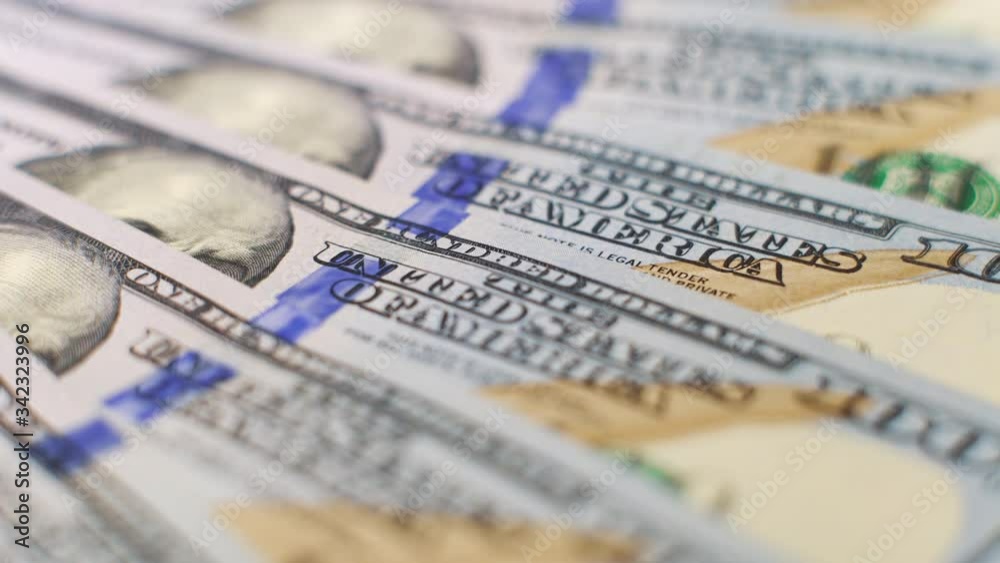 Macro dolly shot of US hundred dollar bills lying accurately on surface Macro dolly shot of US hundred dollar bills lying accurately on surface