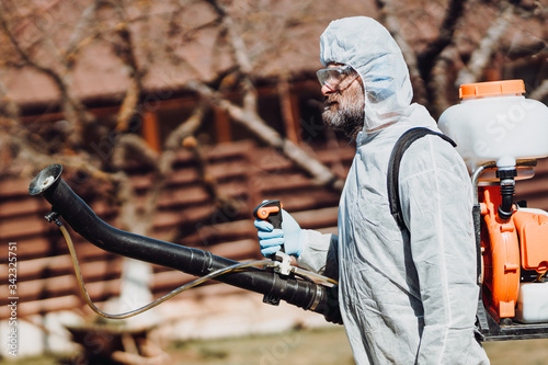 Portrait of industrial worker wearing protective clothing and spraying pesticides, insecticides