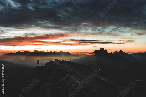 Alba sulla Croda Rossa, sullo sfondo le Tre Cime di Lavaredo. Un'escursionista contempla la bellezza della montagna. photo