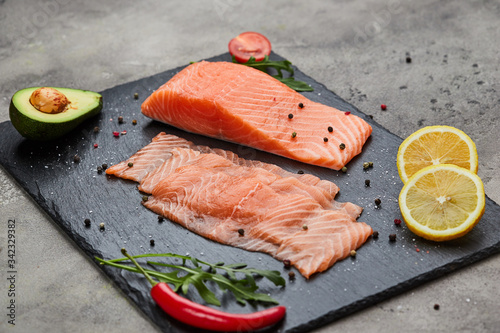 Fresh sliced salmon fillet with arugula, avocado and lemon on slate plate. Wild atlantic fish