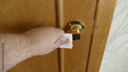man holds a door handle through toilet paper to protect against coronavirus