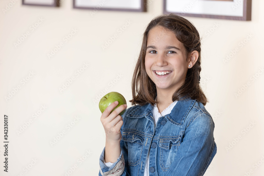 smiling girl looking at the camera holding a green apple smiling girl looking at the camera holding a green apple