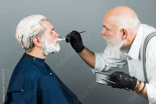Hair coloring man. Making of a dyed blond hair for a bearded hipster guy. Beard coloring man agains grey hair. Bearded man, barber shop.