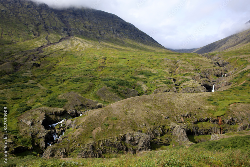 Iceland - August 29, 2017: A stream and mountains along the Ring Road, Iceland, Europe Iceland - August 29, 2017: A stream and mountains along the Ring Road, Iceland, Europe