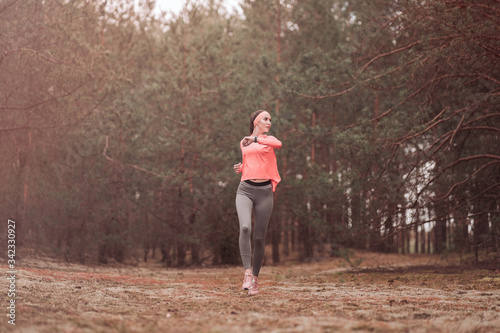 Woman running in the woods. Young girl jogging in a forest. Healthy lifestyle fitness sporty woman running early in the morning. Beautiful young woman runner in pine forest. Healthy lifestyle concept.