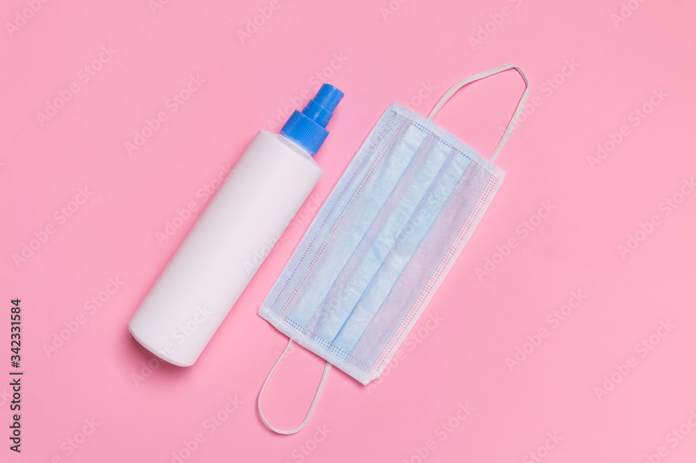 Coronavirus protection. Medical surgical mask and disinfectant or hand sanitizer on pink background. Hygiene measures to prevent spread of Covid-19 pandemic Coronavirus protection. Medical surgical mask and disinfectant or hand sanitizer on pink background. Hygiene measures to prevent spread of Covid-19 pandemic