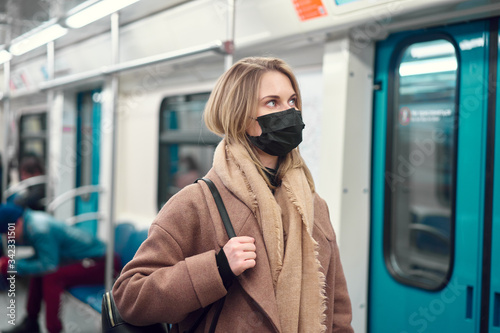 Woman in black medical mask standing in subway near carriage. Coronavirus epidemic.