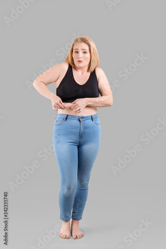 Troubled overweight woman on grey background