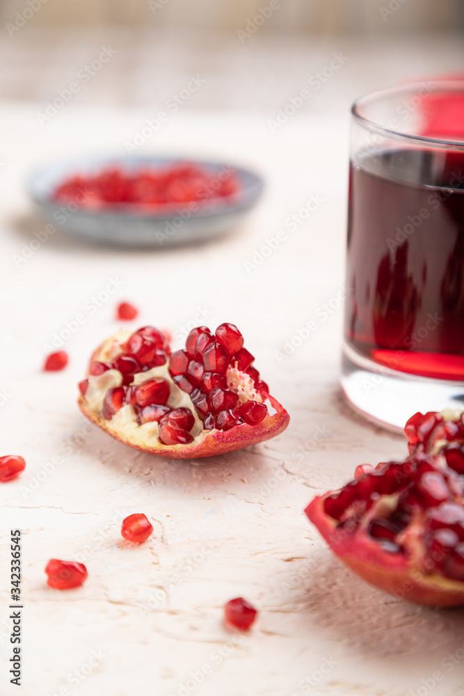 Glass of pomegranate juice on a white concrete background. Side view, selective focus Glass of pomegranate juice on a white concrete background. Side view, selective focus
