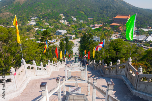 Tian Tan Buddha (Big Buddha) stone stairs. Looking down towards the Ngong Ping Piazza, Lantau Island, Hong Kong, China. Beautiful country flags on a sunny day.