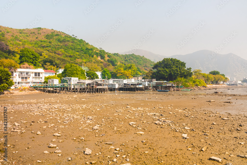 Tai O low tide, Lantau island, Hong Kong, China. Beautiful sunny outdoor shot of the fishing village. Houses on stilts & high mountains in the background.