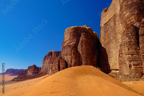 WADI RUM DESERT, JORDAN - FEBRUARY 06, 2020: Sand dunes in the foot of the giant red rocks of Jebel Ishrin photo