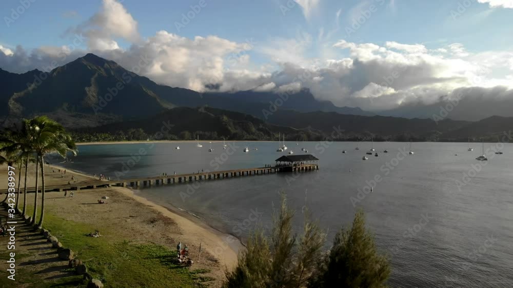 4K drone footage over Hanalei bay, Kauai, Hawaii, with Hanalei Pier and mountains in the back.
Mid angle, traveling movement.