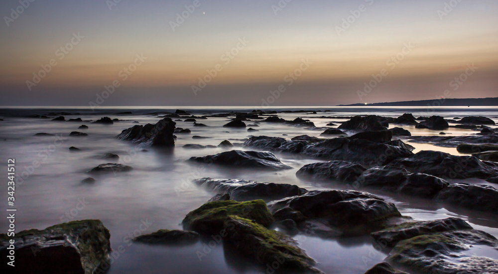 landscape of a beach with rocks at sunset