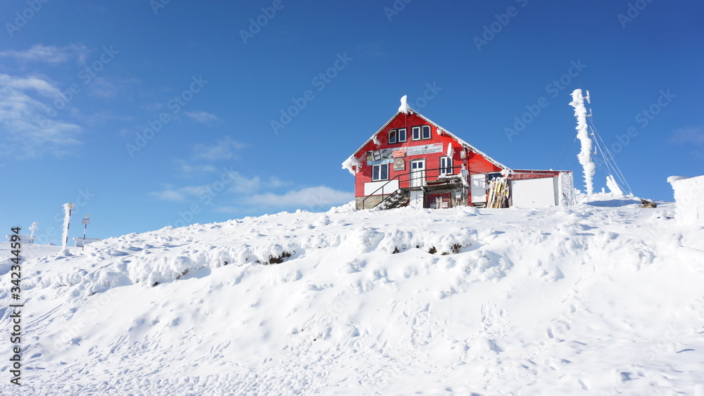 Little beautiful red cabin on the snow with blue sky and white snow 