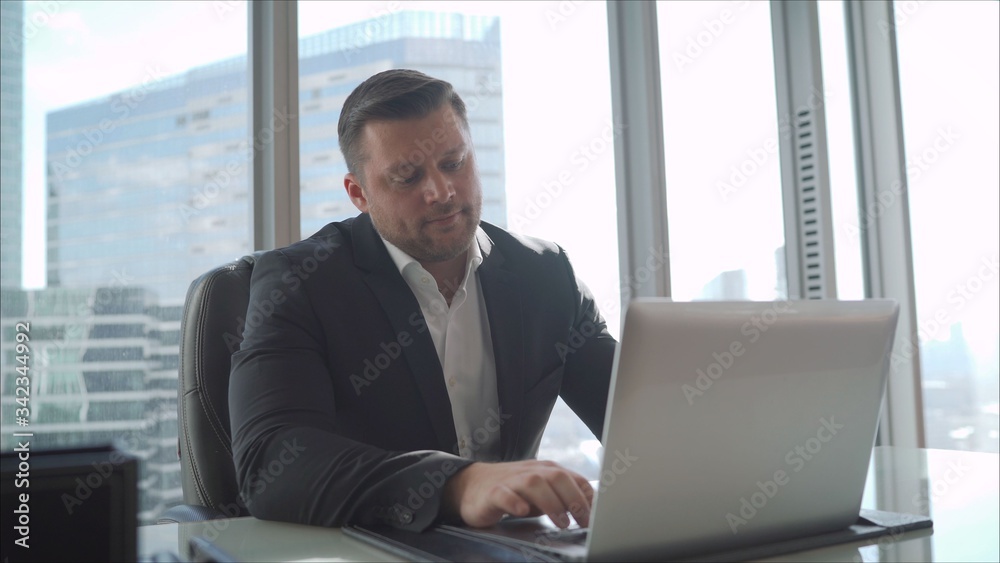 A businessman is sitting at a table in a luxurious office. A businessman in his office on a high floor in a skyscraper. A businessman is sitting at a table in a luxurious office. A businessman in his office on a high floor in a skyscraper.