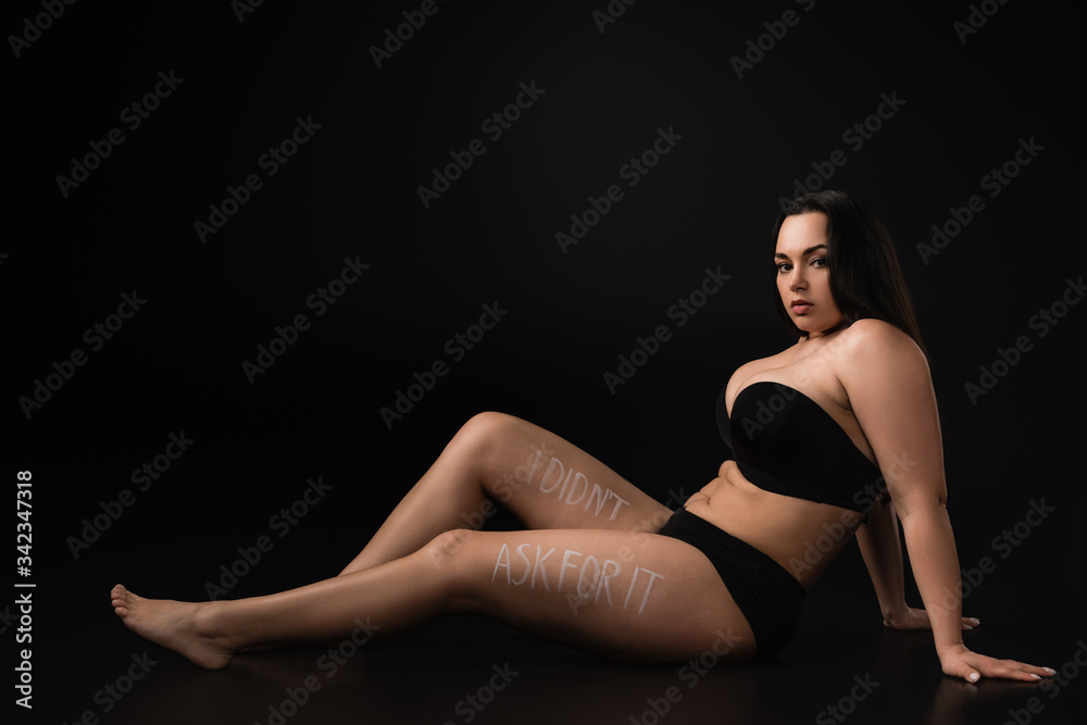 Side view of plus size model with lettering I Did not Ask For It on body on black background