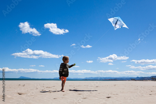 Happy boy running on the beach in summer with a kite. Beautiful sea and sand