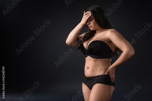 Plus size girl in underwear with facepalm gesture on black background © LIGHTFIELD STUDIOS