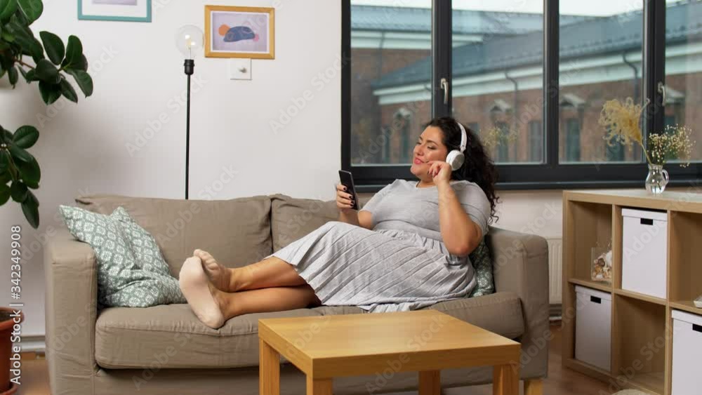 technology, people and leisure concept - happy young woman in headphones listening to music on smartphone at home technology, people and leisure concept - happy young woman in headphones listening to music on smartphone at home