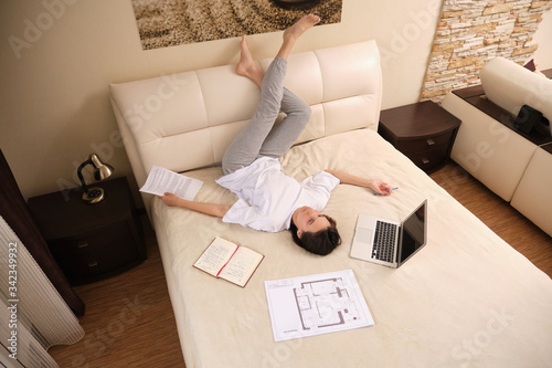 Young  woman businessman on self-isolation during a coronovirus pandemic COVID-19 on self-isolation works at home, lying on bed, checks mail, does his work remotely, telework photo