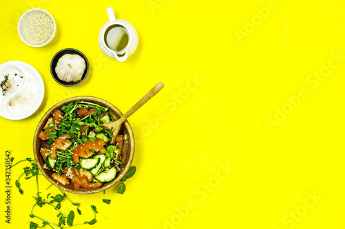 Veggie vegetable salad in a wooden bowl on a yellow background, top view, flat lay