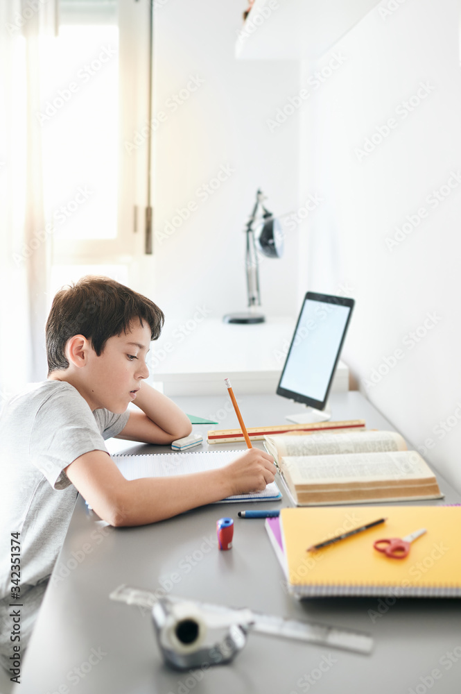Stress kid doing homework.Boy at study table doing homework with stress action.Lazy boy doing homework with stressed face.