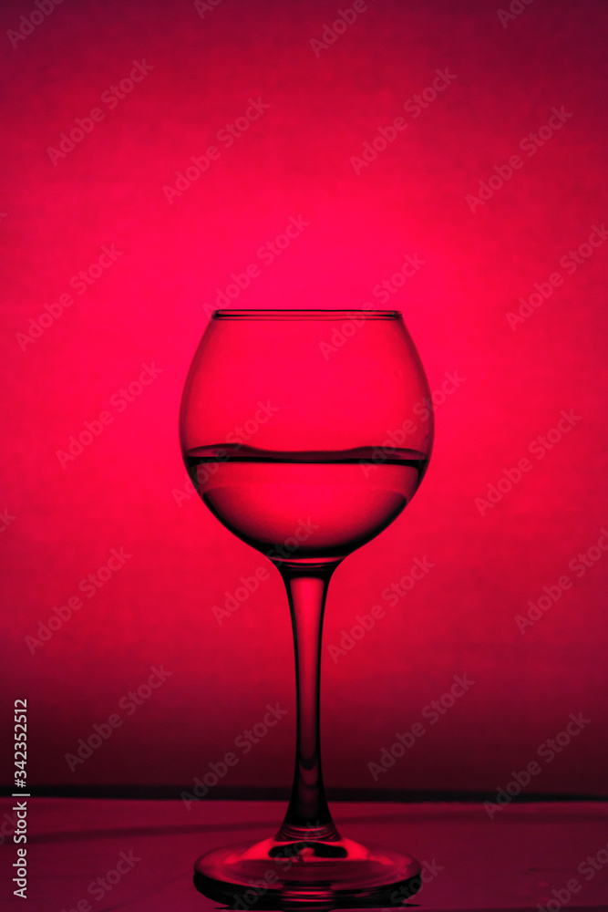 Wine glass with liquid on a red background. Backgrounds and textures. Wine glass with liquid on a red background. Backgrounds and textures.