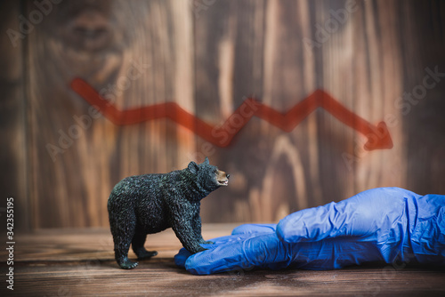 Stock symbols on a brown wooden background. Chart, bear and blue gloves symbolizing the coronavirus pandemic. Covid-19

