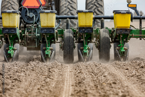 Photo Closeup of tractor and planter in farm field planting corn or soybeans seed in d
