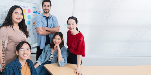 Smart asian startup small entrepreneur  standing confident portrait with  friends partner casual meeting brainstorm with white board and business financce paper chart anslysis in office background photo