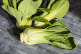 Fresh green bok choy or pac choi chinese cabbage on a gray wooden background. Side view.