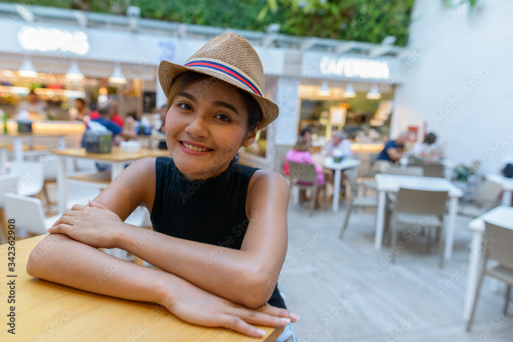 Happy young Asian tourist woman smiling at the restaurant outdoors