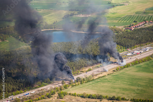 Fire on highway  - strong black smoke rises to the sky, flames are visible - two trucks caught fire on a highway and burn out completely - aerial view  © Mario Hagen