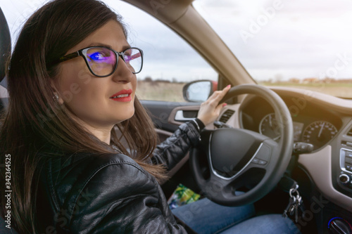 Young beautiful woman with glasses driving a car, going in high speed. photo