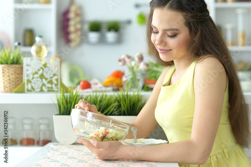 Portrait of cute girl eating salad on kitchen