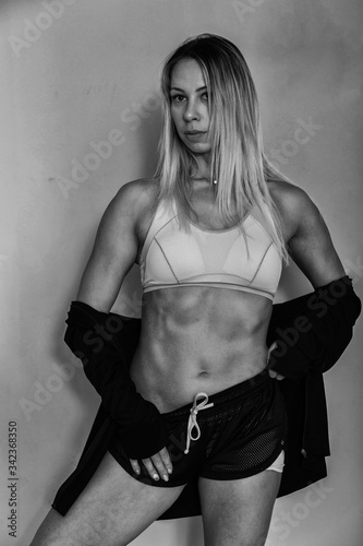 Sports muscular woman portrait wearing black sportswear over grey. Attractive sexy caucasian woman with long blond hair in studio shot.
