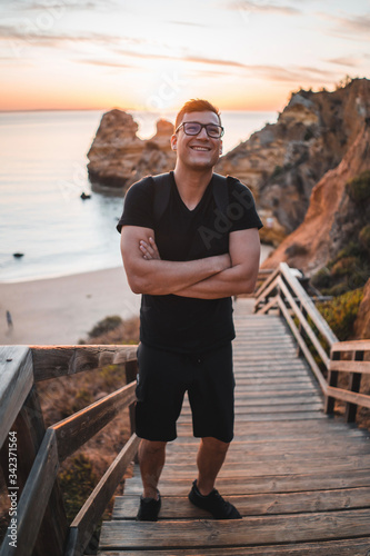 A men smiles on the sandy beach of Praia di Camilo in Portugal