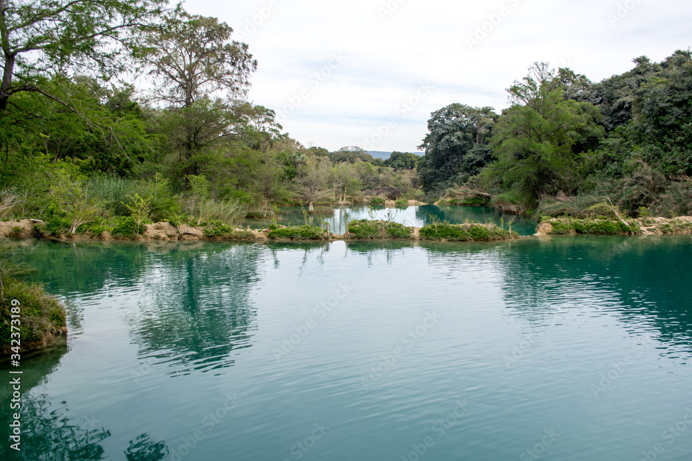 Conjunto de lagunas de agua color turquesa con formaciones de piedra caliza cubiertas de plantas en medio de la selva en México en el Salto, Huasteca Potosina, San Luis Potosí
