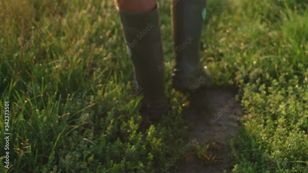 a person walks through a field with rubber boots a person walks through a field with rubber boots
