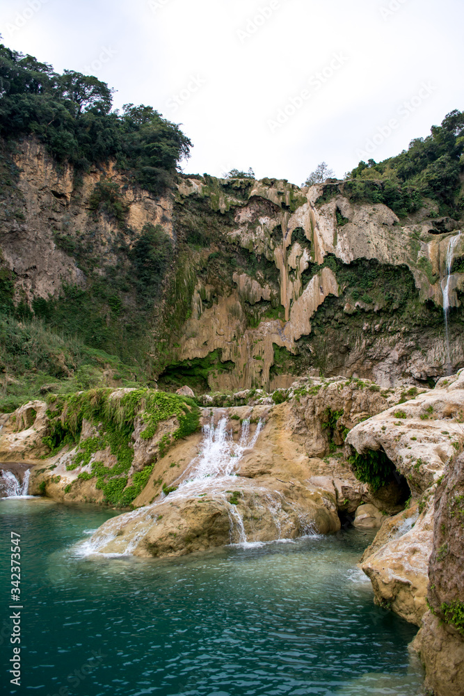 Toma vertical de la cascada el salto con poca agua cayendo y las pozas de agua turquesa  descubiertas y llenas de agua cubiertas por helechos en México en la Huasteca Potosina en San Luis Potosí 