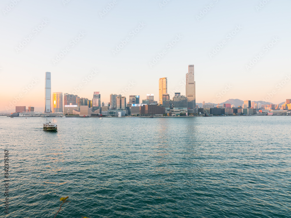 Obraz premium Tsim Sha Tsui Waterfront from the Wan Chai Ferry Pier, Hong Kong. Beautiful sunset shot of the South China Sea and buildings in the background (Cultural art center, K11 Musea, etc...). 